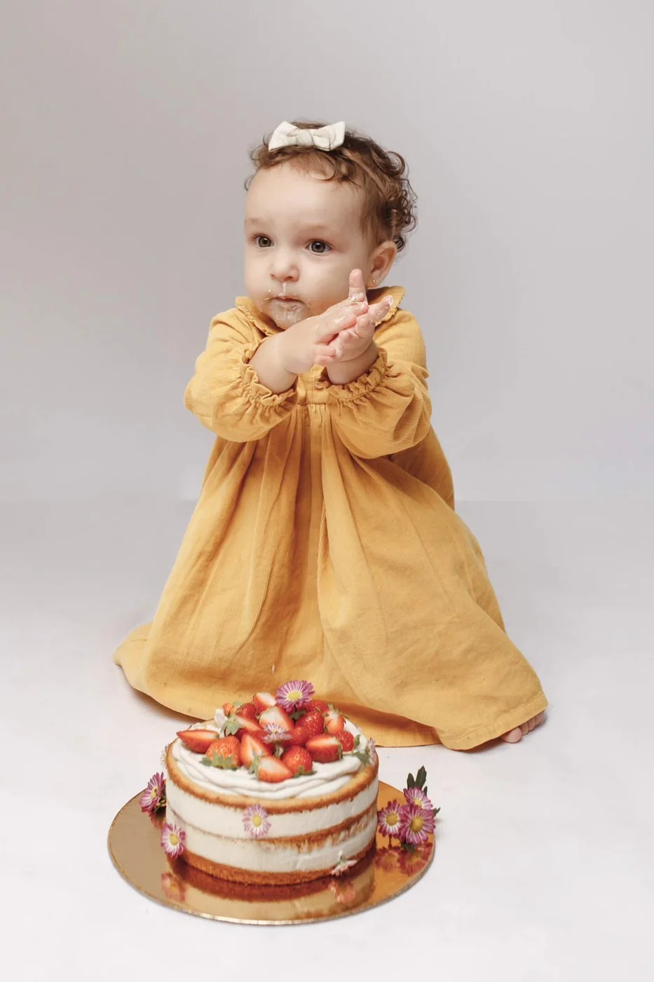 Bebé junto de um bolo de morangos